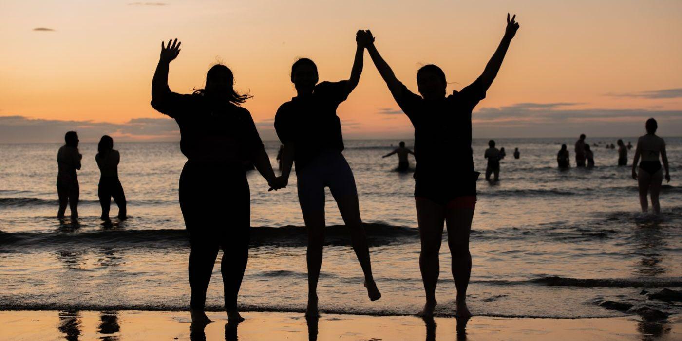 Students jumping in the sea at sunrise