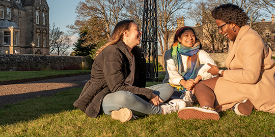 students sitting on grass talking