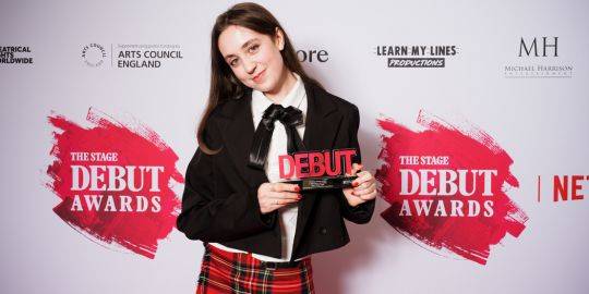 Milly poses for a photo with her Stage Debut Award, the award displays the word 'DEBUT' written in hot pink Milly poses for a photo with her Stage Debut Award, the award displays the word 'DEBUT' written in hot pink