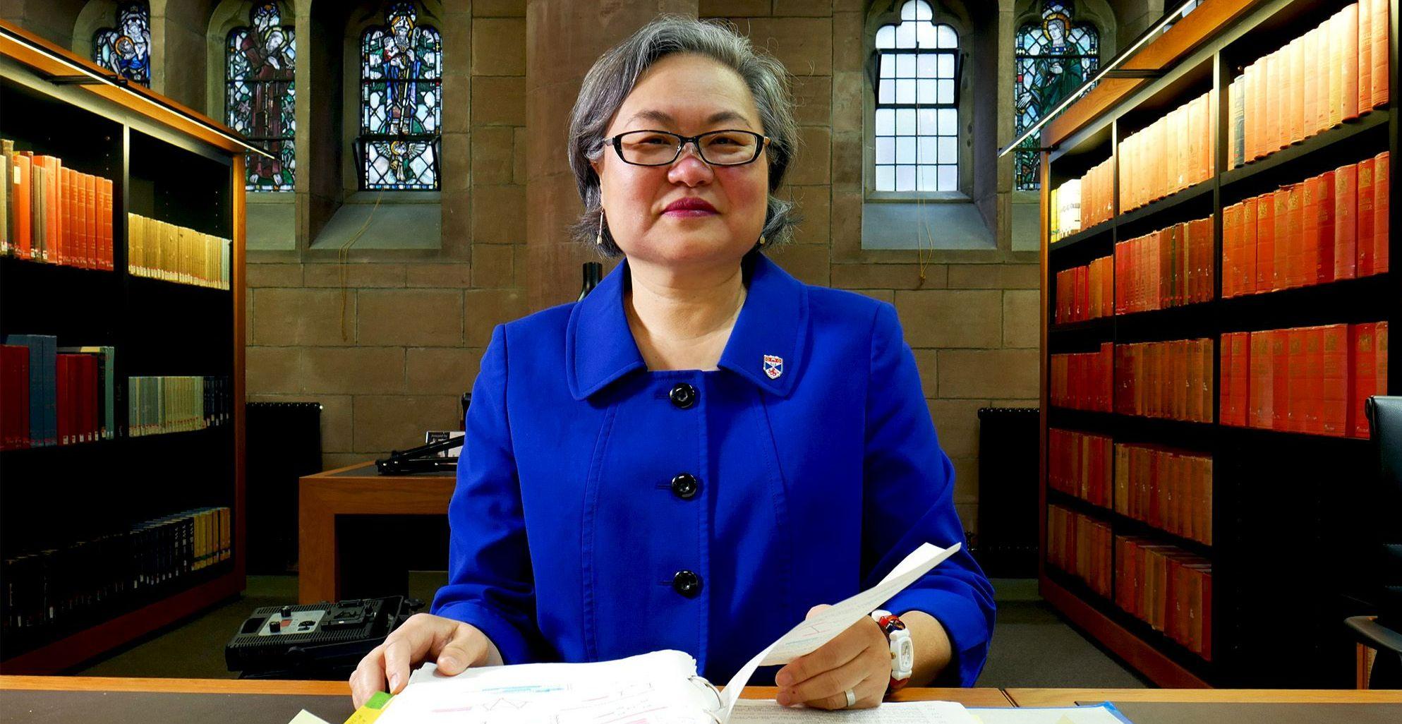 Helen Hwang, pictured in a historic library wearing a blue suit Helen Hwang, pictured in a historic library wearing a blue suit