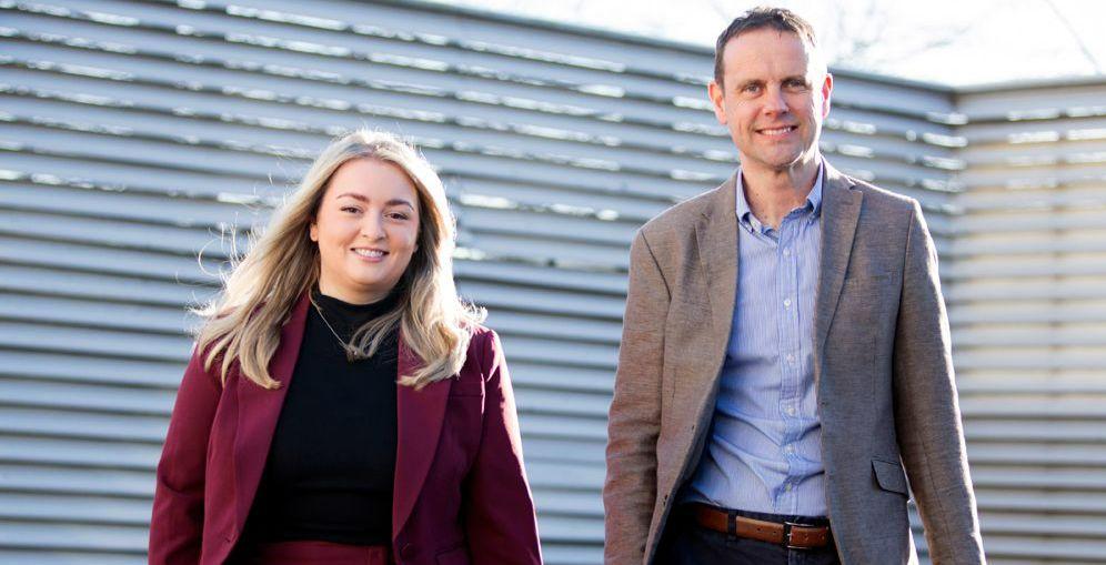 Melissa (left) and Stephen (right) can be seen walking, smiling towards the camera, both are wearing business attire.