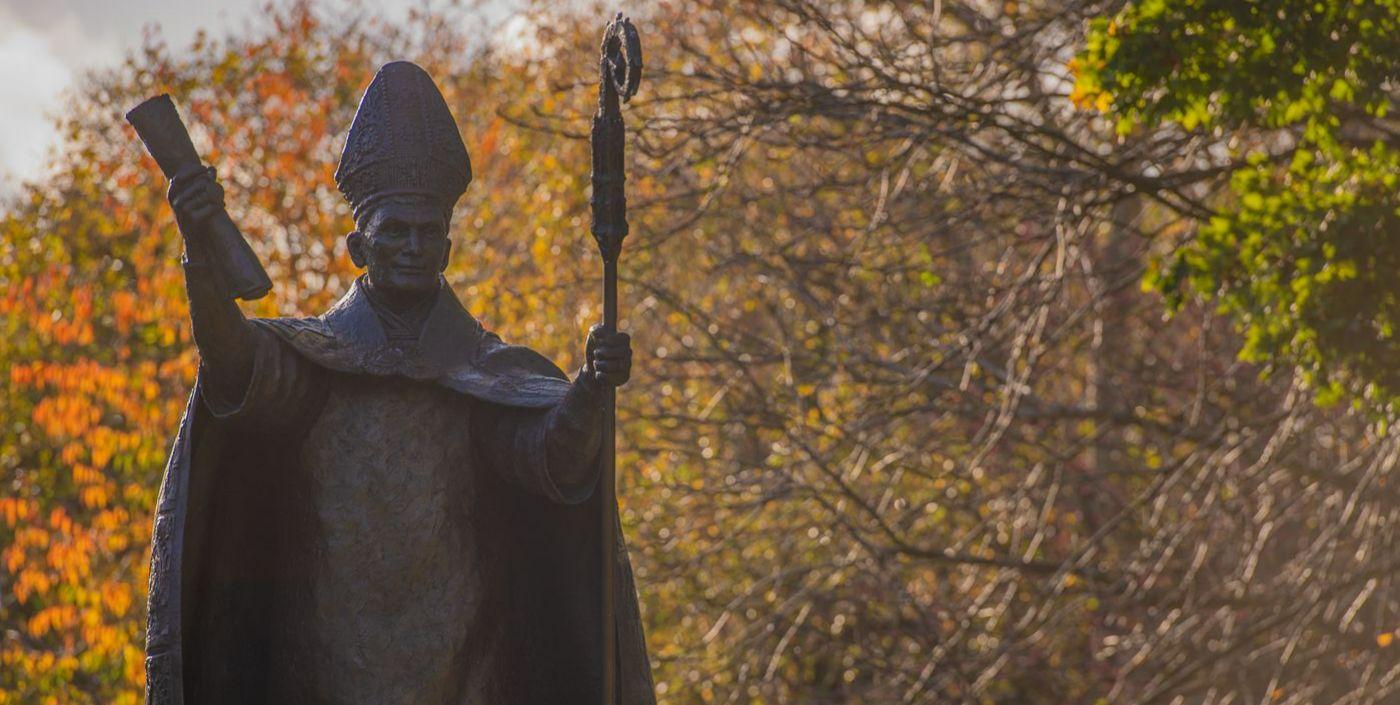 Statue of Bishop Wardlaw with a background of autumn leaves on trees