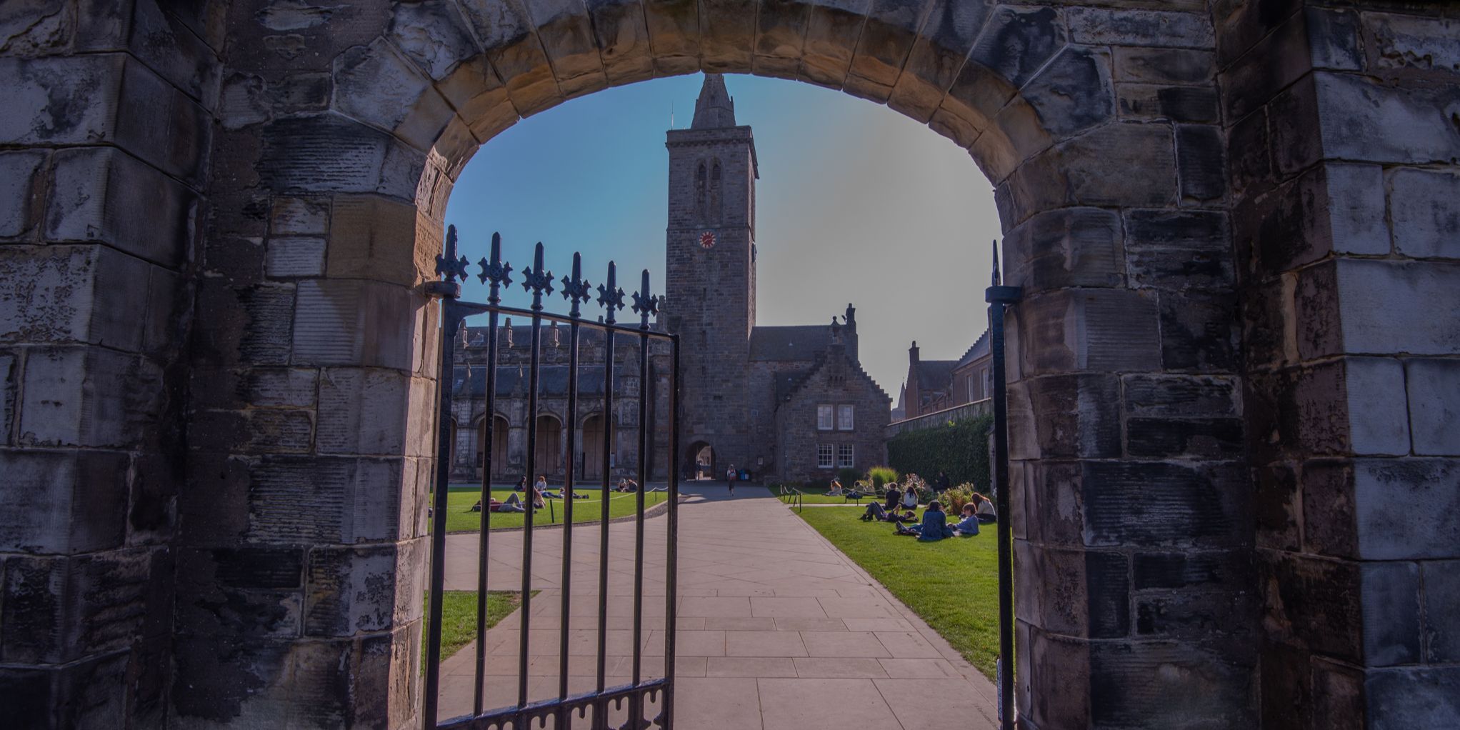 View from gate into St Salvator's Quad. Students can be seen sitting on the grass with St Salvator's tower framed in the centre of the image View from gate into St Salvator's Quad. Students can be seen sitting on the grass with St Salvator's tower framed in the centre of the image