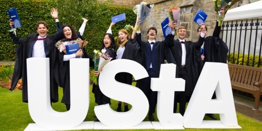 Graduates pose with UStA (University of St Andrews) large lettering in St Salvator's Quad Graduates pose with UStA (University of St Andrews) large lettering in St Salvator's Quad