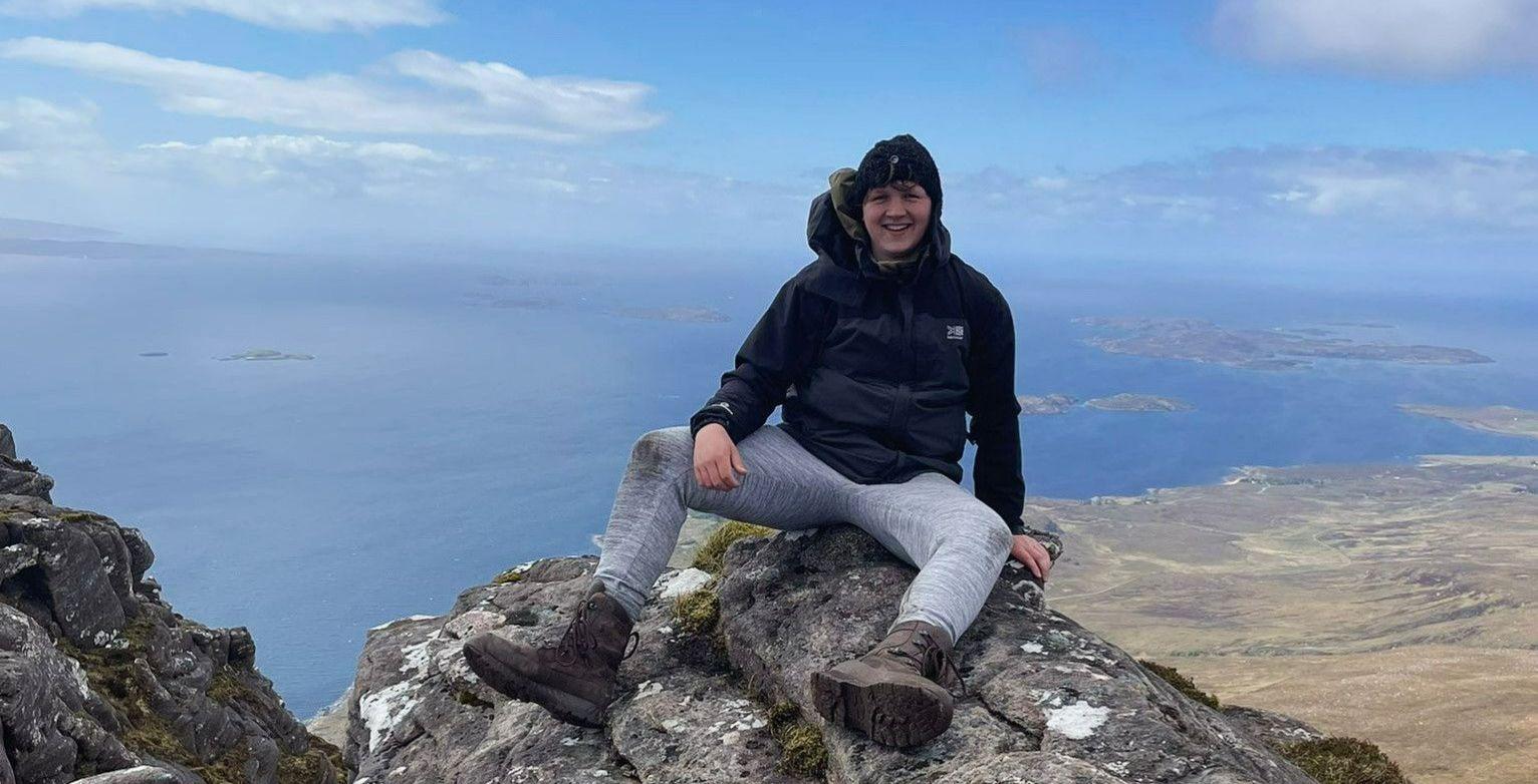 man sitting a top mountain