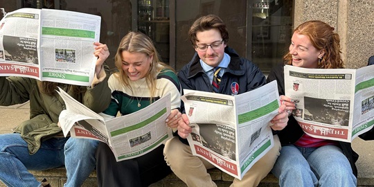 four students reading The Saint student newspaper