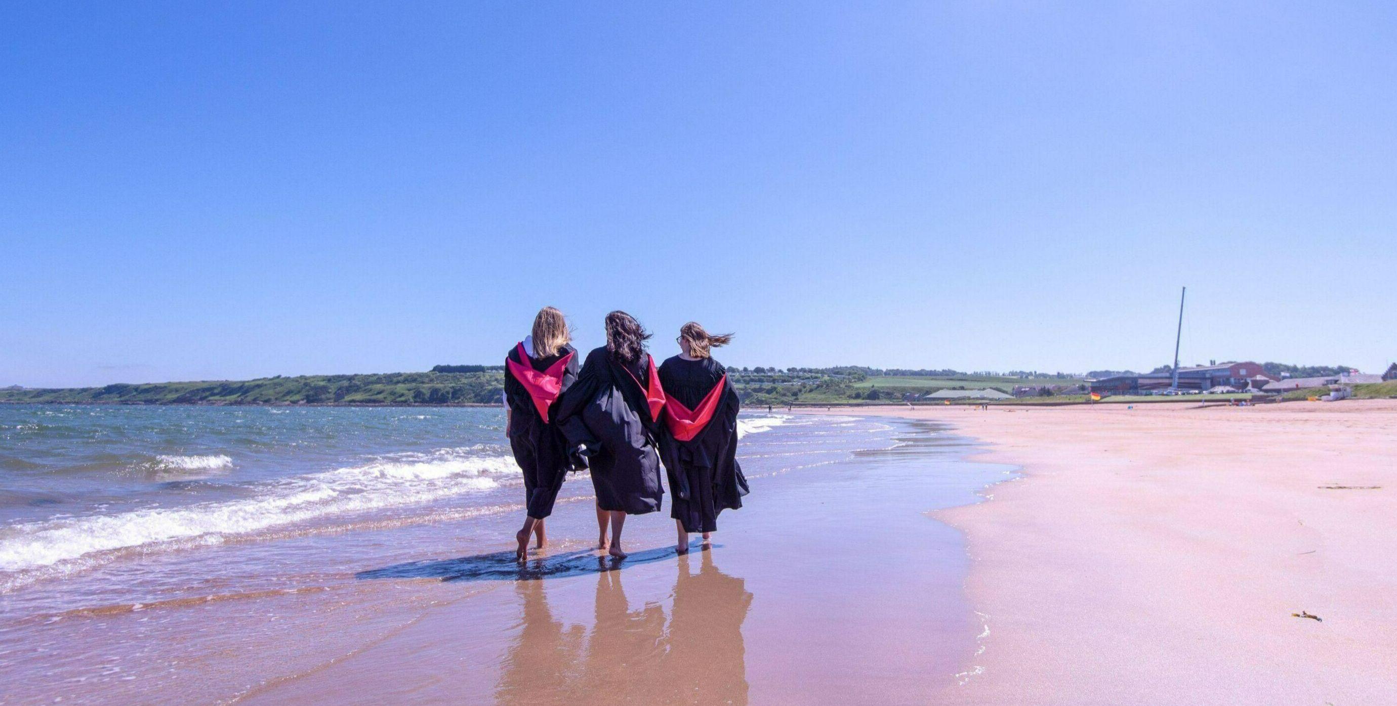 Three students walking on beach