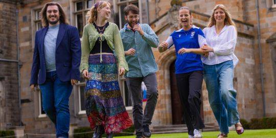 Five Sabbatical Officers walk through St Salvator's Quad, they can be seen to be smiling and laughing. 