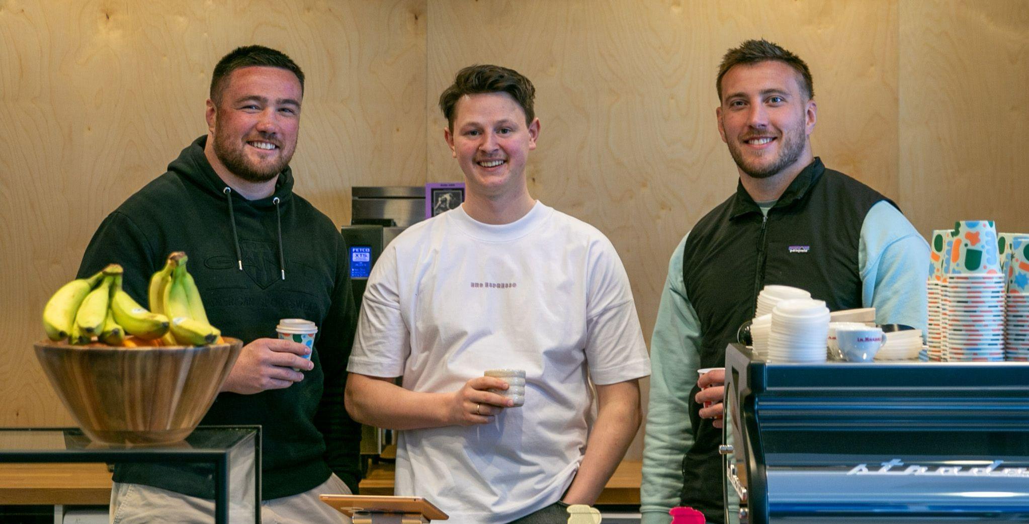 Three people standing behind a coffee bar Three people standing behind a coffee bar